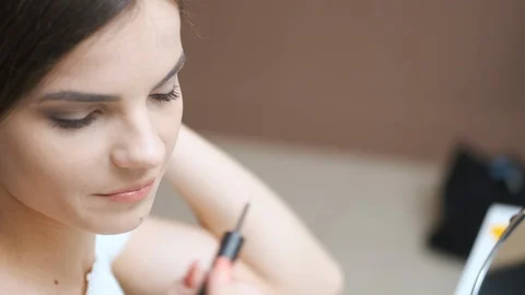 Girl draws eyelashes while looking in the mirror Video stock 129178434