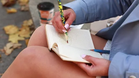 A girl draws a heart in a notebook while sitting in an autumn park Stock Footage 292959441