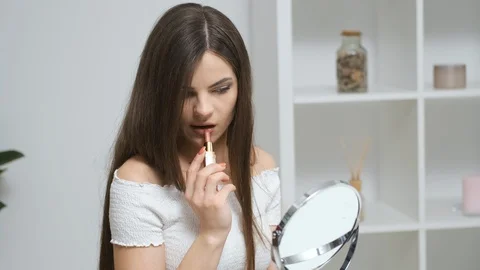 Girl draws her lips while looking in the mirror Stock Footage 129046259