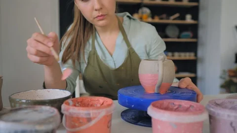 The girl draws a pattern on a clay cup closeup.  Painting of clay products Vídeo Stock 119545505