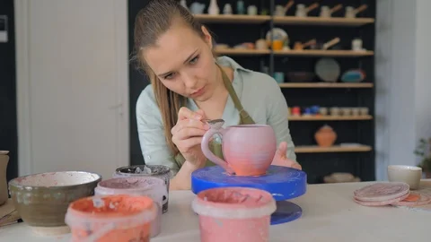 The girl draws a pattern on a clay cup closeup.  Painting of clay products Stock Footage 119546148