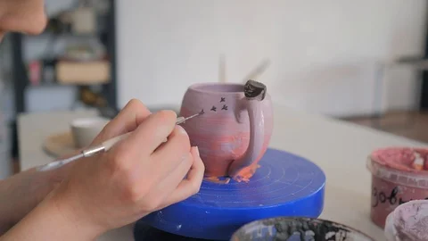 The girl draws a pattern on a clay cup closeup.  Painting of clay products 库存影片 119546216