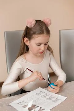 A girl draws a pattern on a colored egg. Home preparations for Easter holiday Foto stock