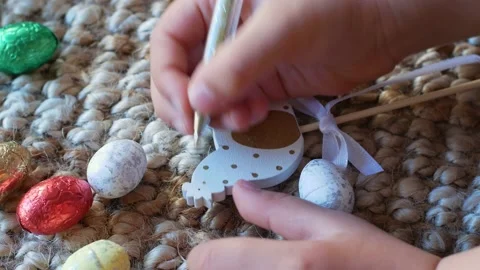 A girl draws a pattern on an Easter decoration in the form of a bunny with Stock Footage 176287687