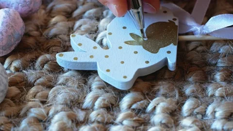 A girl draws a pattern on an Easter decoration in the form of a bunny with Stock Footage 176295216