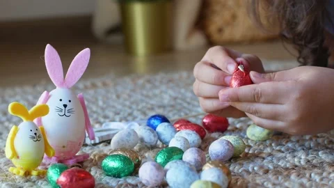 Girl draws a pattern on an Easter egg next to an egg in the shape of a rabbit Stock Footage 176290210