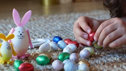 Girl draws a pattern on an Easter egg next to an egg in the shape of a rabbit Stock Footage 176291298