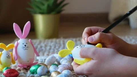 A girl draws a pattern on an Easter egg in the form of a rabbit with Easter eggs Stock Footage 176293218