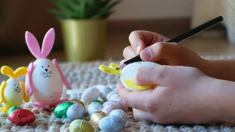 A girl draws a pattern on an Easter egg in the form of a rabbit with Easter eggs Stock Footage 176293817