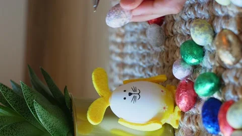 Girl draws a pattern on an Easter egg next to an egg in the shape of a rabbit Stock Footage 176296533