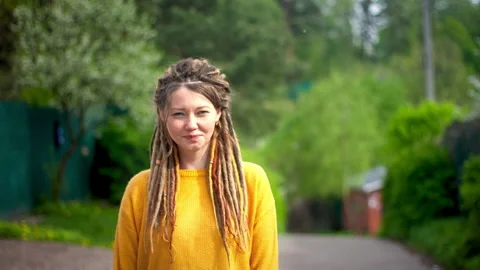 Girl with dreadlocks smiling on the background of a spring park Stock Footage 131001772