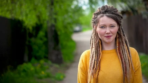 Girl with dreadlocks smiling on the background of a spring park Stock Footage 131001773