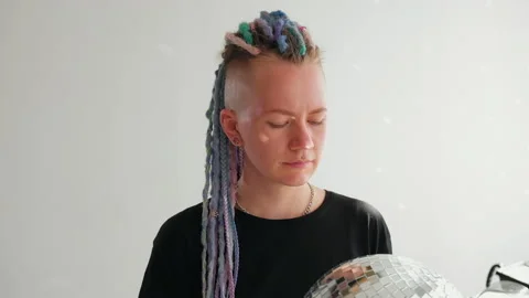 A girl with dreadlocks is standing in a white studio with a disco ball Video stock 183995150