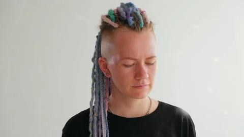 A girl with dreadlocks is standing in a white studio with a disco ball Stock Footage 183998933