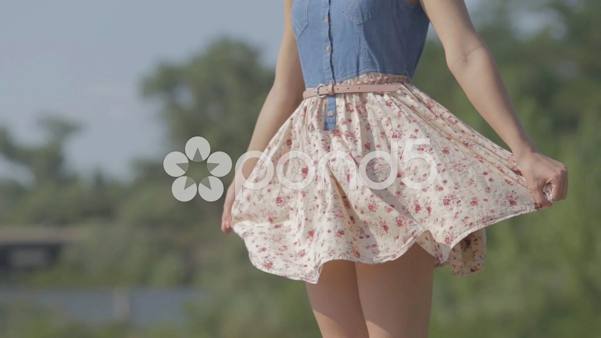 girl in a dress stands near the river and the wind lifts her dress