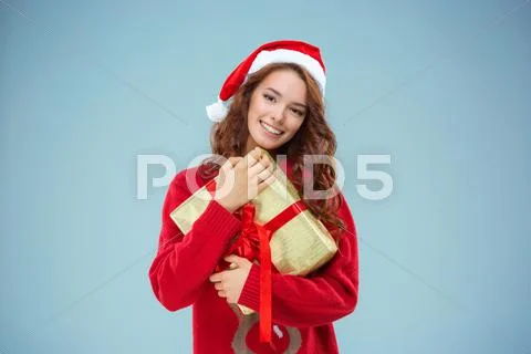 Girl dressed in santa hat with a Christmas gift Stock Photos