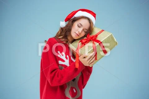 Girl dressed in santa hat with a Christmas gift Stock Photos