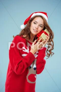 Girl dressed in santa hat with a Christmas gift Stock Photos