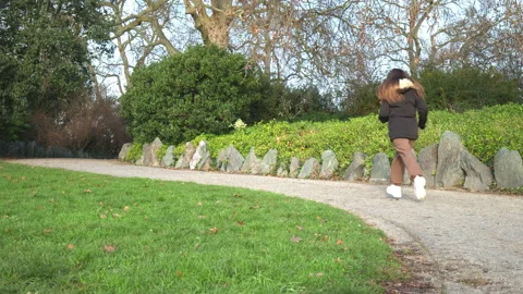 A girl dressed in a winter jacket running in the green park. Stock Footage 146493955