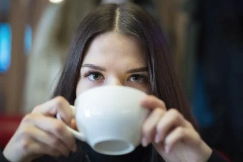A girl is drinking coffee in a cafe. Small depth of field Foto stock