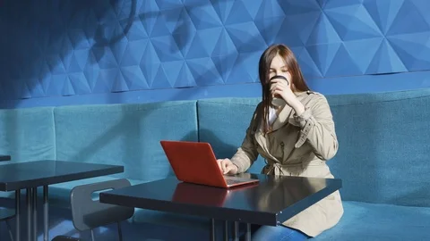 Girl drinking coffee. Surprised looking laptop and comparing information phone Stock Footage 126654392