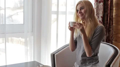 Girl drinking coffee while sitting in a chair by the window Stock-Footage 60781200