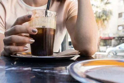 A girl drinking cold coffee while talking at hot summer day Stock Photos