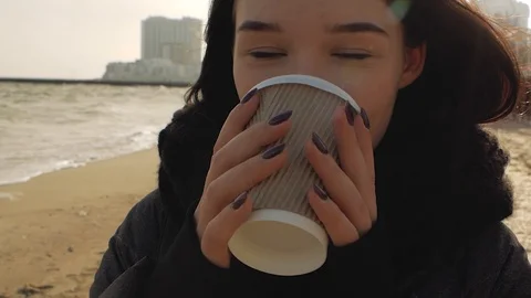 Girl drinking from a disposable cup of tea near the sea Stock Footage 102605484