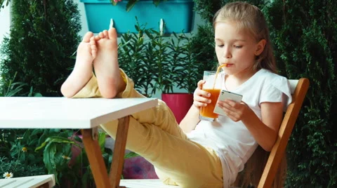 Girl drinking juice and using cell phone and smiling at camera Video stock 51883785