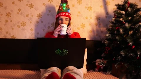 Girl drinking tea in front of laptop by fireplace at Christmas Stock Footage 257199088