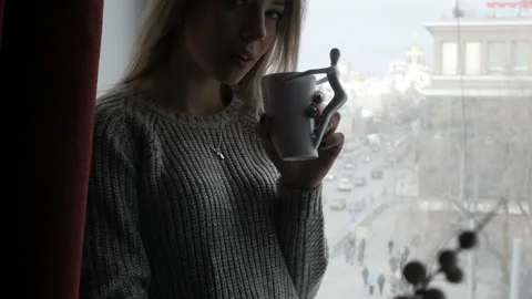 Girl is drinking tea on window sill Video stock 85969239
