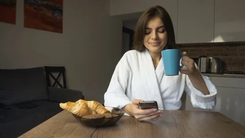 Girl Drinks Coffee and Uses Smartphone Stock Footage