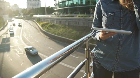 The girl drinks coffee and uses a tablet computer. Big city. Car traffic Stock Footage 142264053