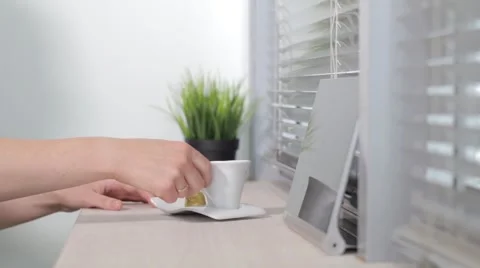 Girl drinks coffee from a white mug and beautiful prints on the tablet Stock Footage