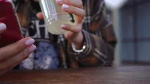 Girl drinks lemonade while sitting at a table on the street Video stock 139131056