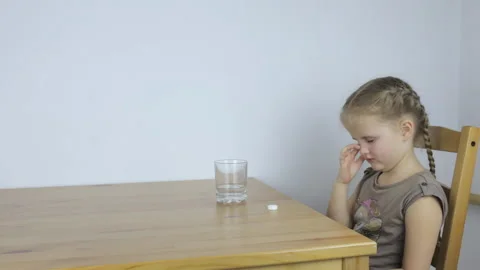 Girl drinks a tablet with water while sitting at the table Video stock 101380708
