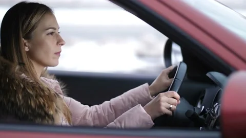 The girl drives the car, stops at the intersection, looks at the road goes Stock-Footage 100401824