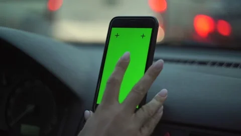 Girl driving a car clicks an application on a phone with a green screen Stock Footage 139517005