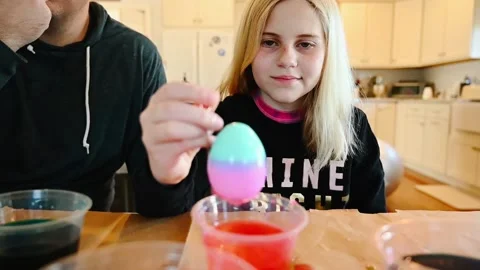 Girl dyeing Easter eggs in kitchen at table Video stock 152729519