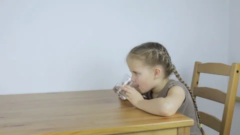 Girl eagerly drinks water while sitting in the kitchen Video stock 101380782