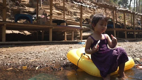 Girl eating bread at streams Stockbeeldmateriaal 124813846