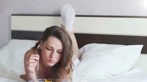 Girl eating chips lying on the bed Stock Footage 65204538