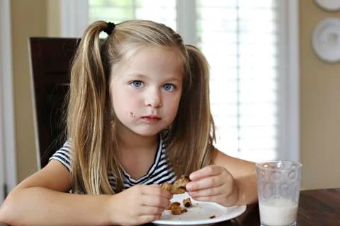 Girl eating cookie on table Stock Photos