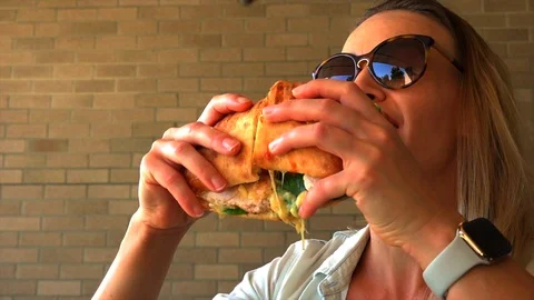 Girl eating a delicious sandwich outdoors in summer Stock Footage