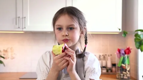 A girl eats apple in a cozy kitchen. Stock Footage 304913382
