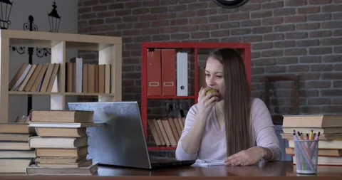 Girl eats apple at workplace in office, freelancer girl works in home office Stock Footage 130366801