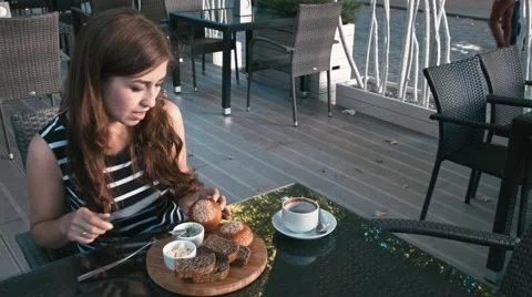 The girl eats a bagel and drinking coffee Stock Footage 66171298