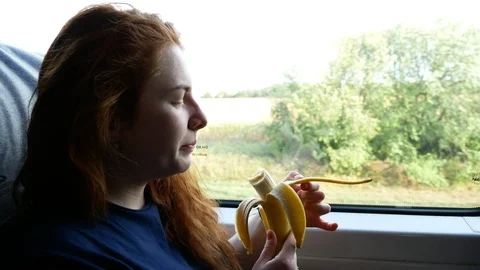 Girl eats a banana by the window of the train Stock Footage 114831765