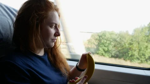 Girl eats a banana by the window of the train Stock Footage 114831831