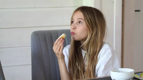A girl eats a bread and butter for breakfast. A girl with long hair in a white T Stock Footage 311022436